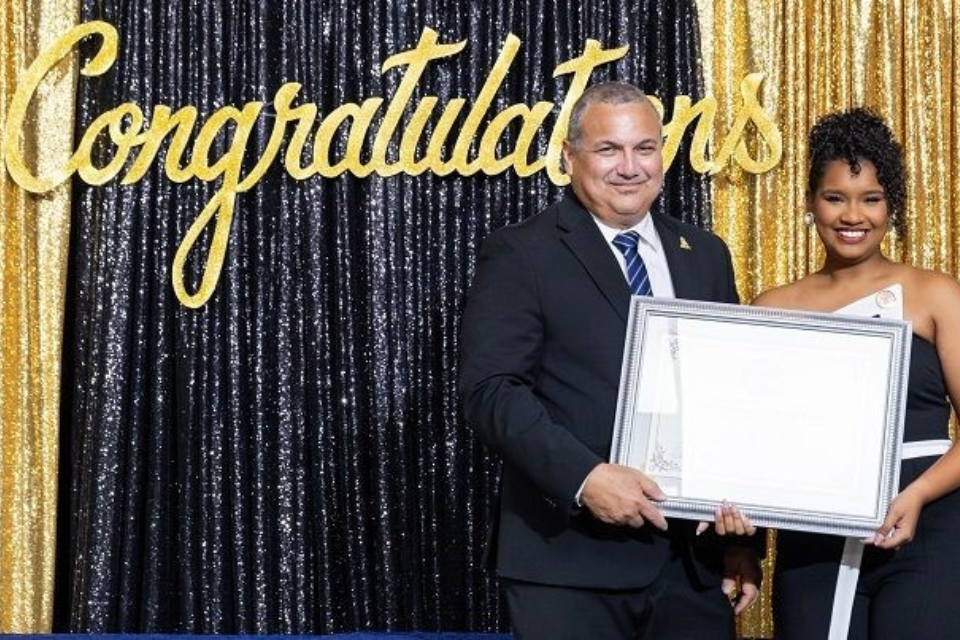 Employee of the year 2023 accepting her award on stage with deputy governor Franz Manderson.