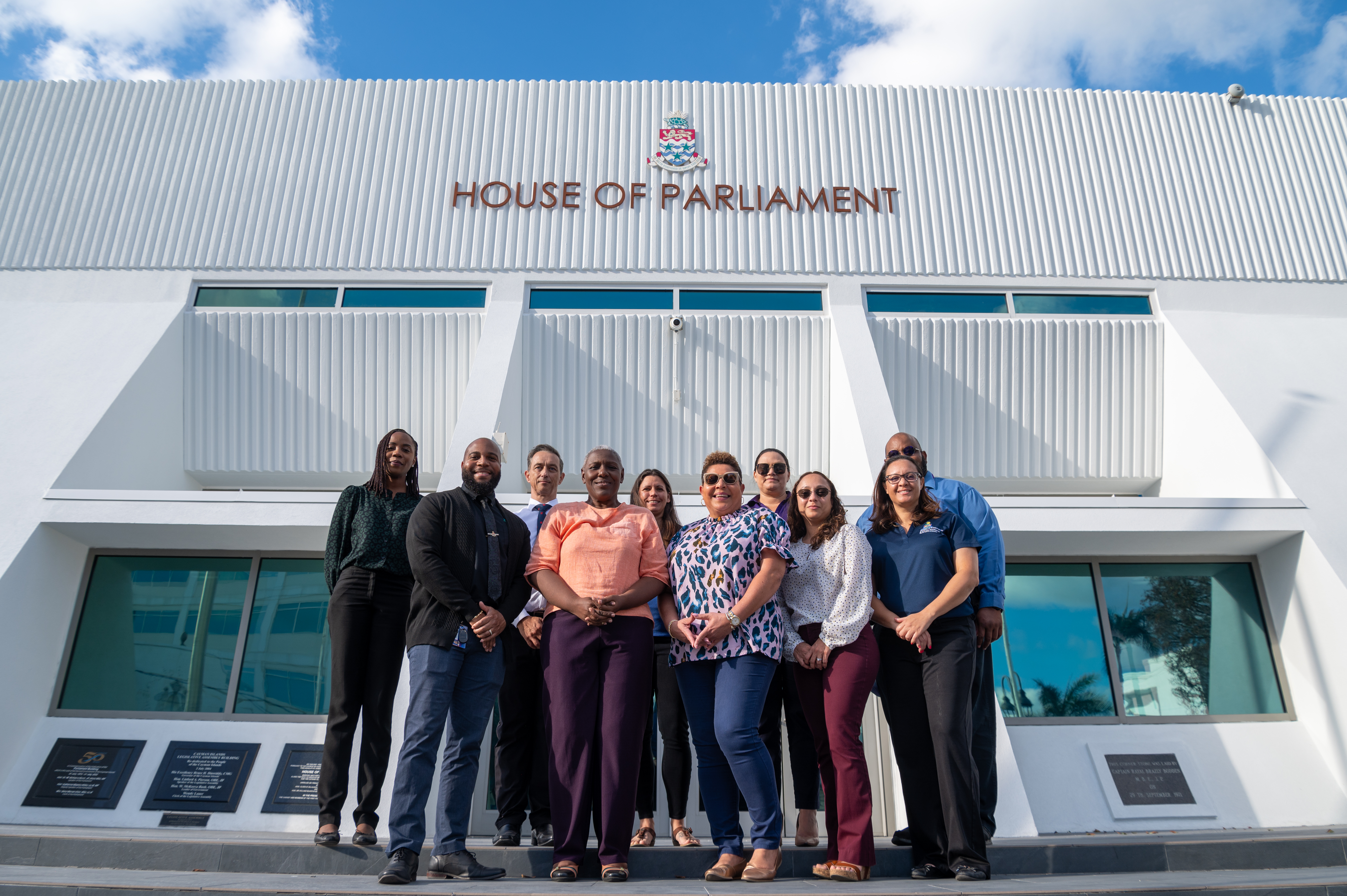 Group of Civil Servants and Minister Stand infront of the House Of Parliament in Grand Cayman