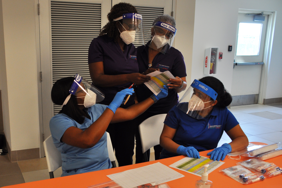 The Poinciana Health Works at a table comparing stats and info Centre in Grand Cayman Ribbon Cutting Ceremony with the Premier, Various Ministers and Deputy Governor 