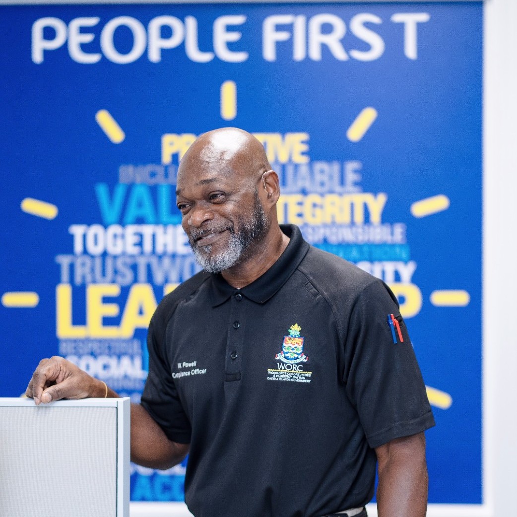 Cayman Islands Government WORC Compliance Officer Powell infront of people first sign.