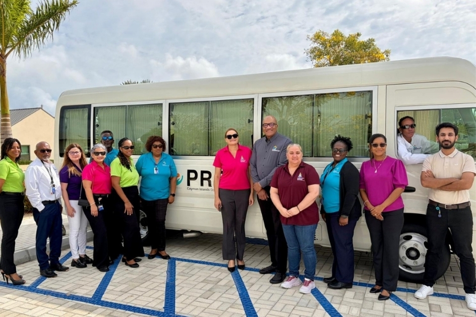 Minister for Health, Environment and Sustainability, Honourable Katherine Ebanks-Wilks accompanied by Chief Officer Tamara Ebanks, PRC Director, Marcia Mullings-Thompson, PRC Clinical Director, Dr. Marc Lockhart along with other Ministry and PRC team members with the new Toyota Coaster bus that strengthens the services available to residents at the facility.